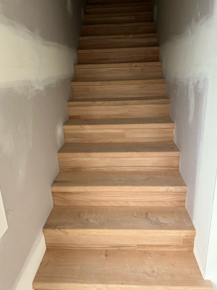 A set of wooden stairs leading up to a white wall — Building Services in Rockhampton