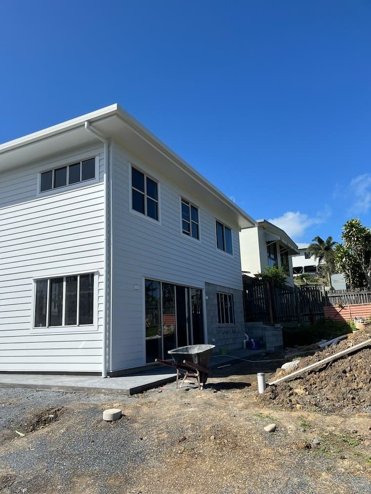 A large white house with a wheelbarrow in front of it — Building Services in Rockhampton