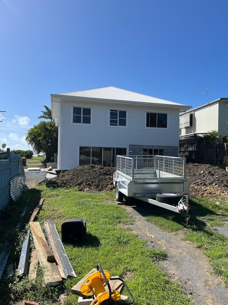A large white house with a trailer parked in front of it — Building Services in Rockhampton