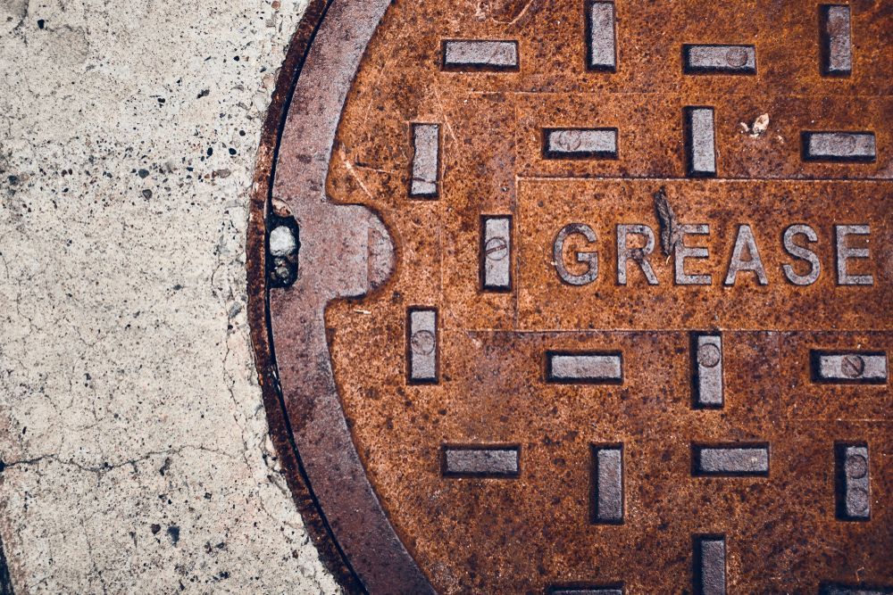 A Man in a Cowboy Hat is Pumping Water Into a Manhole Cover — Proserpine Septic Service In Cannonvale, QLD