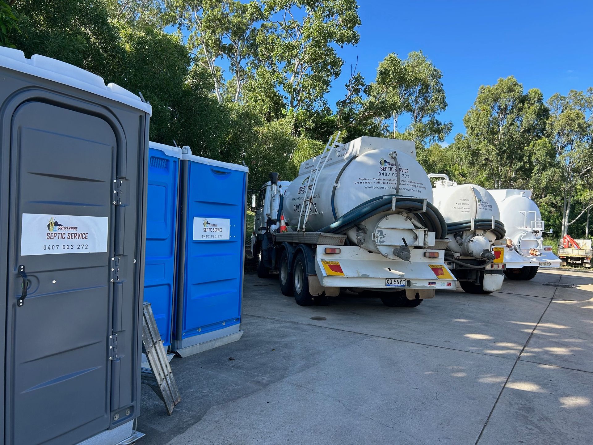 A Row of Trucks Are Parked in a Parking Lot Next to Portable Toilets — Proserpine Septic Service In Cannonvale, QLD