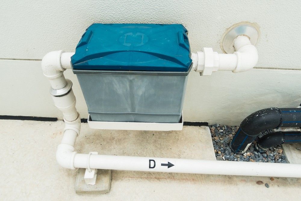 A Blue Box is Attached to a White Pipe on the Side of a Building — Proserpine Septic Service In Cannonvale, QLD