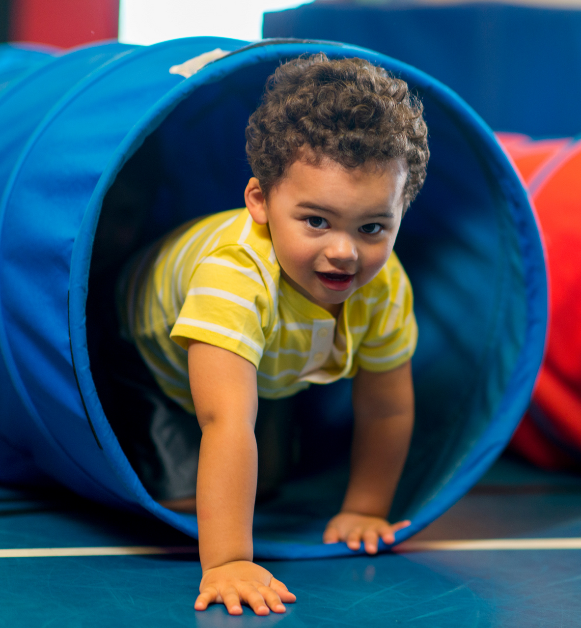 A young boy is crawling through a blue tunnel