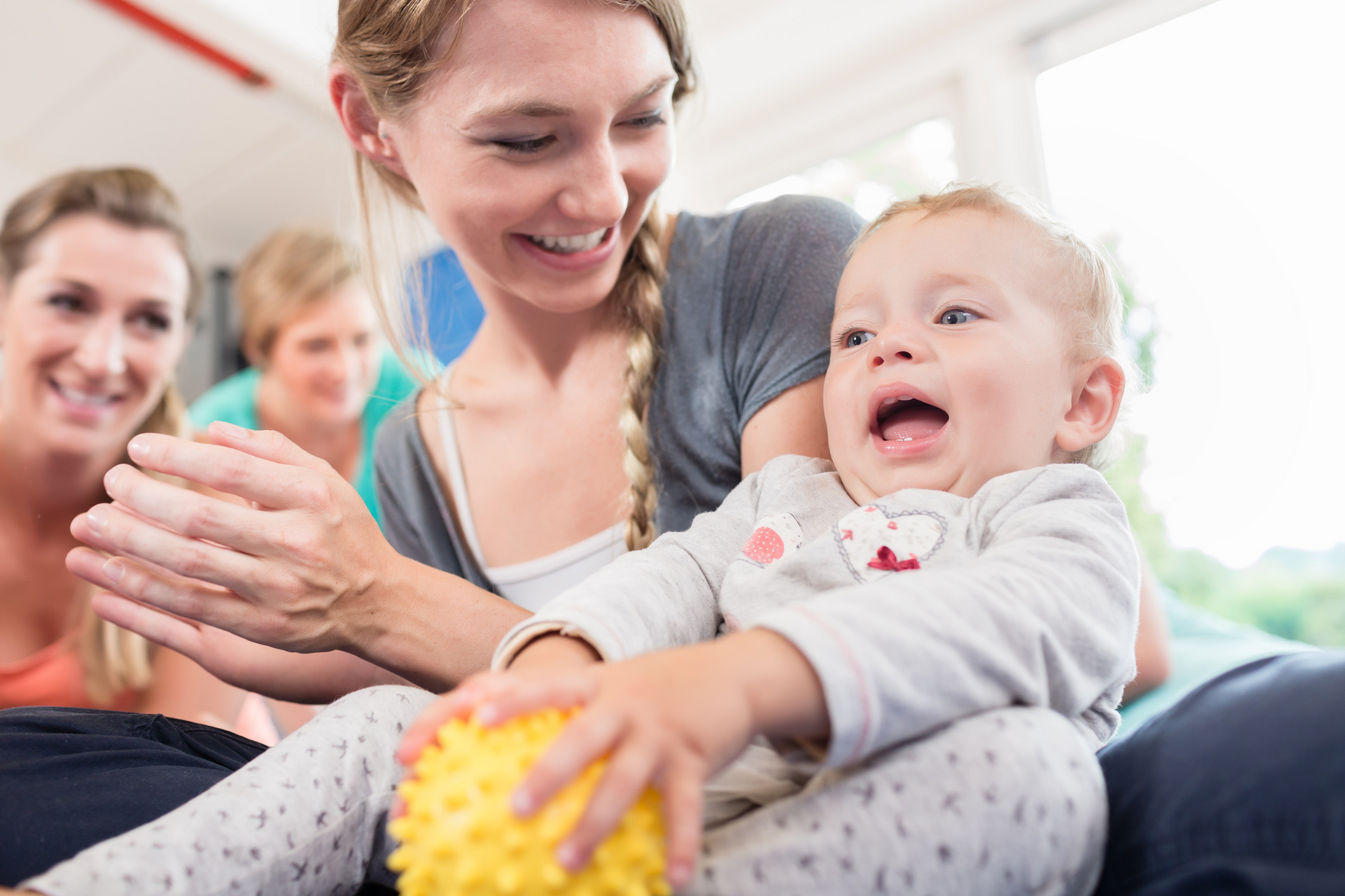 A woman is holding a baby and playing with a ball.