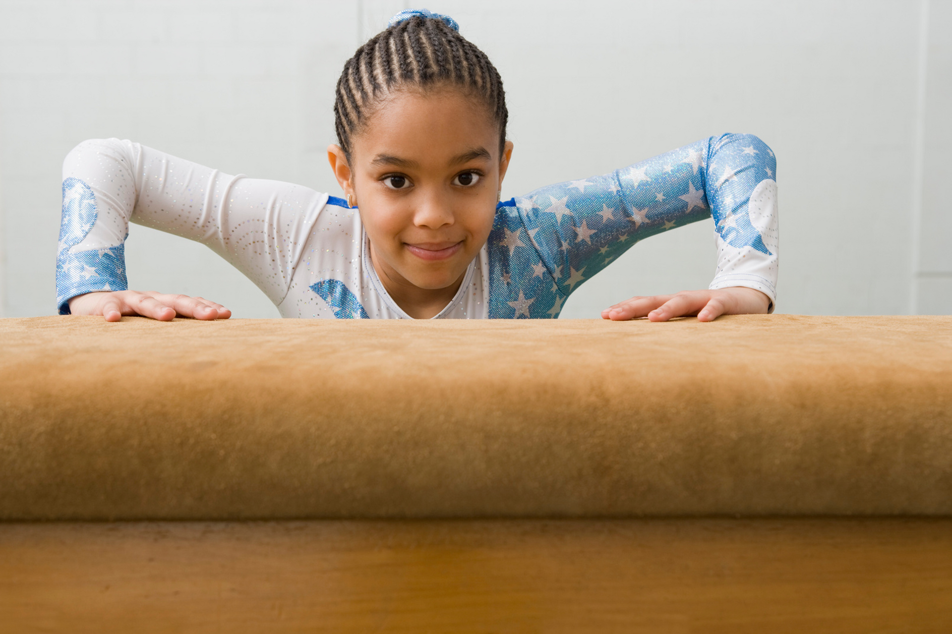 A young girl is standing on a balance beam.
