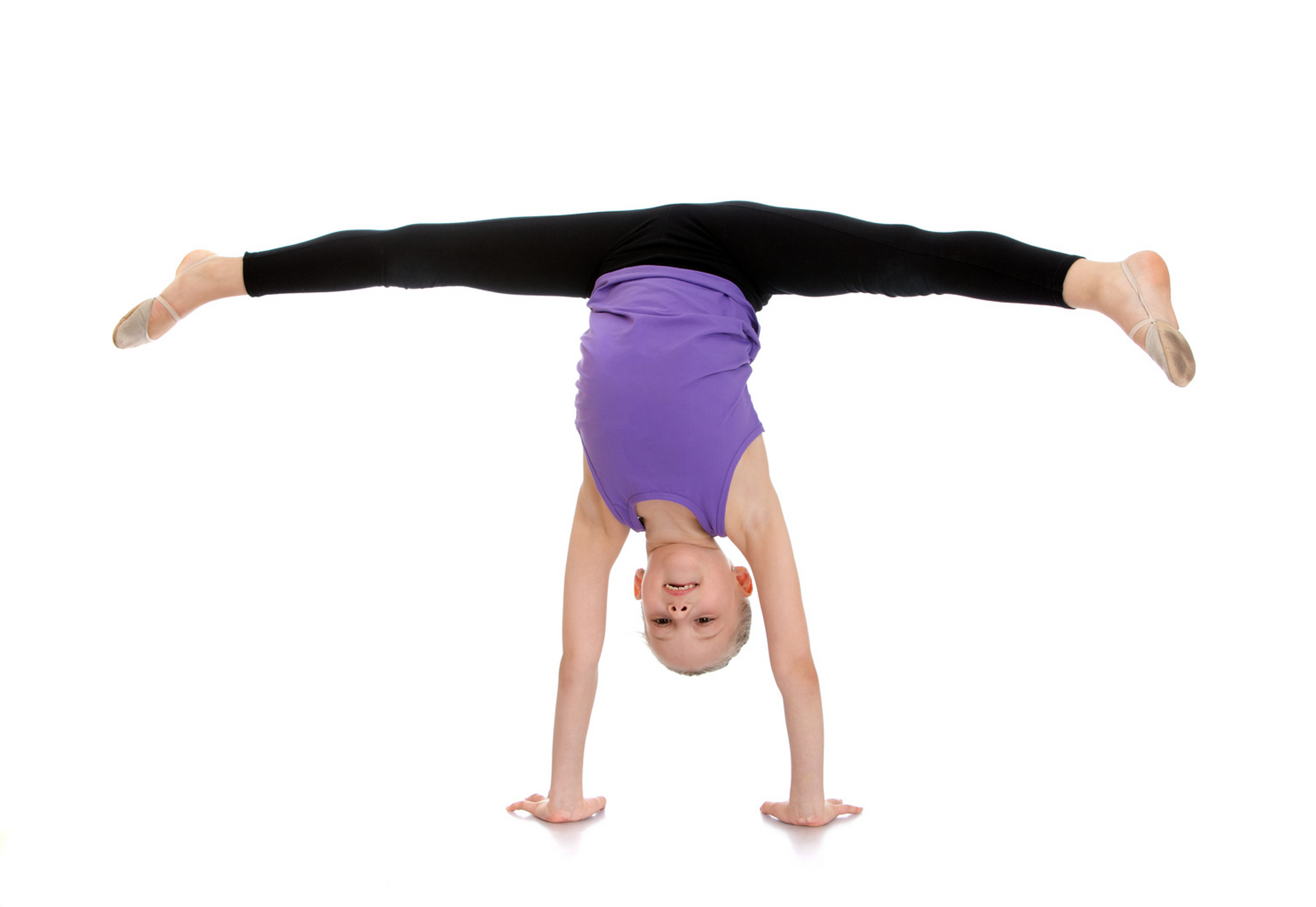 A young girl is doing a handstand on a white background.