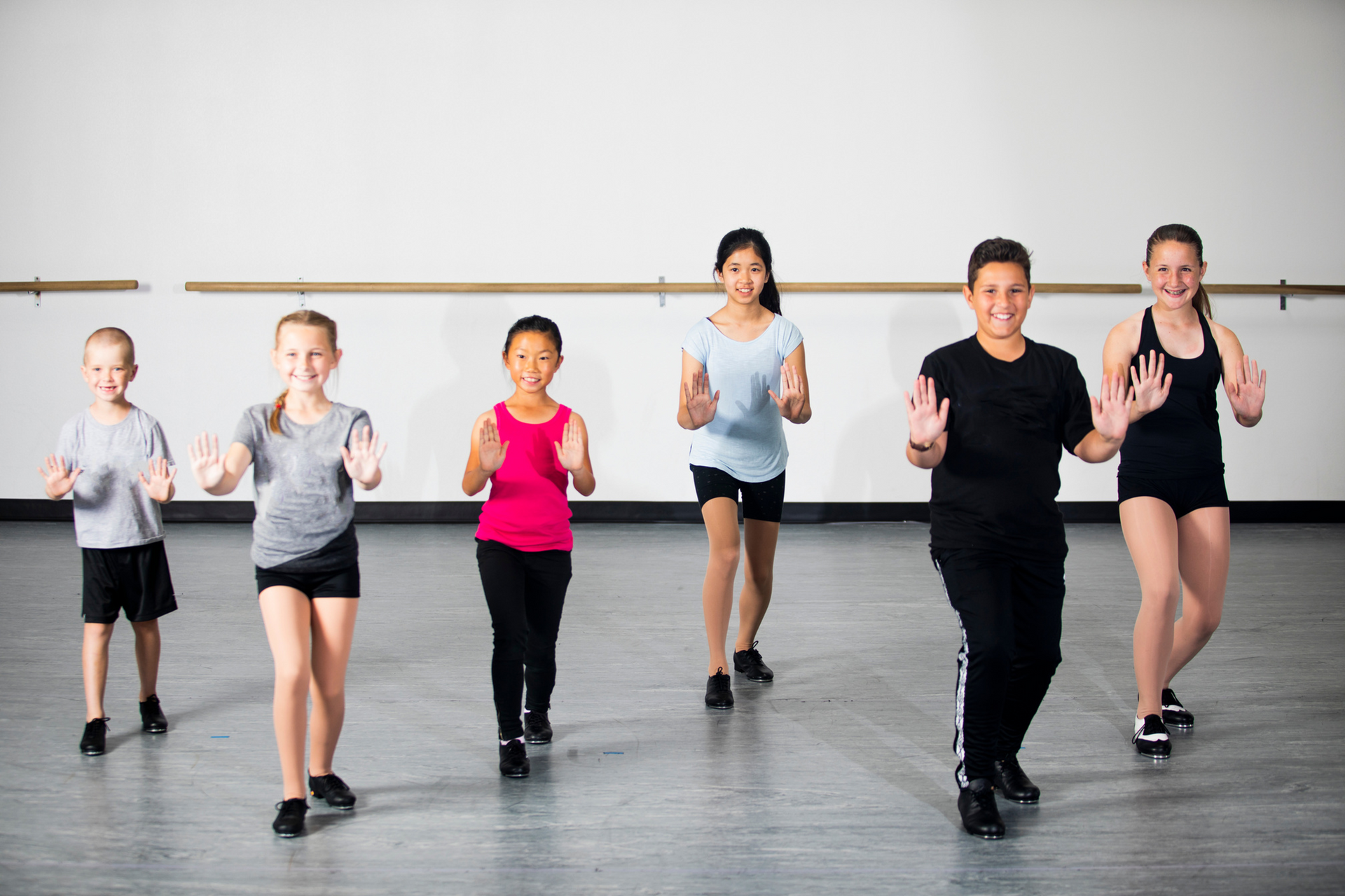 A group of children are dancing together in a dance studio.