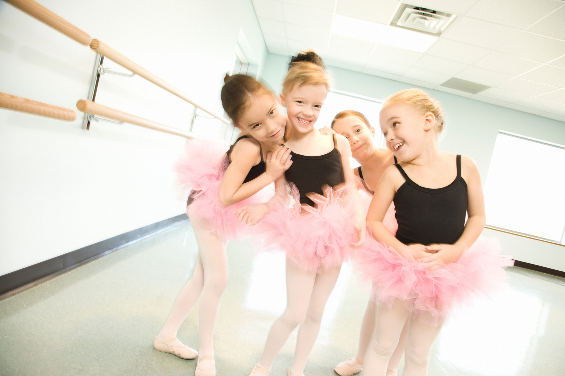 A group of young ballerinas are posing for a picture in a dance studio.
