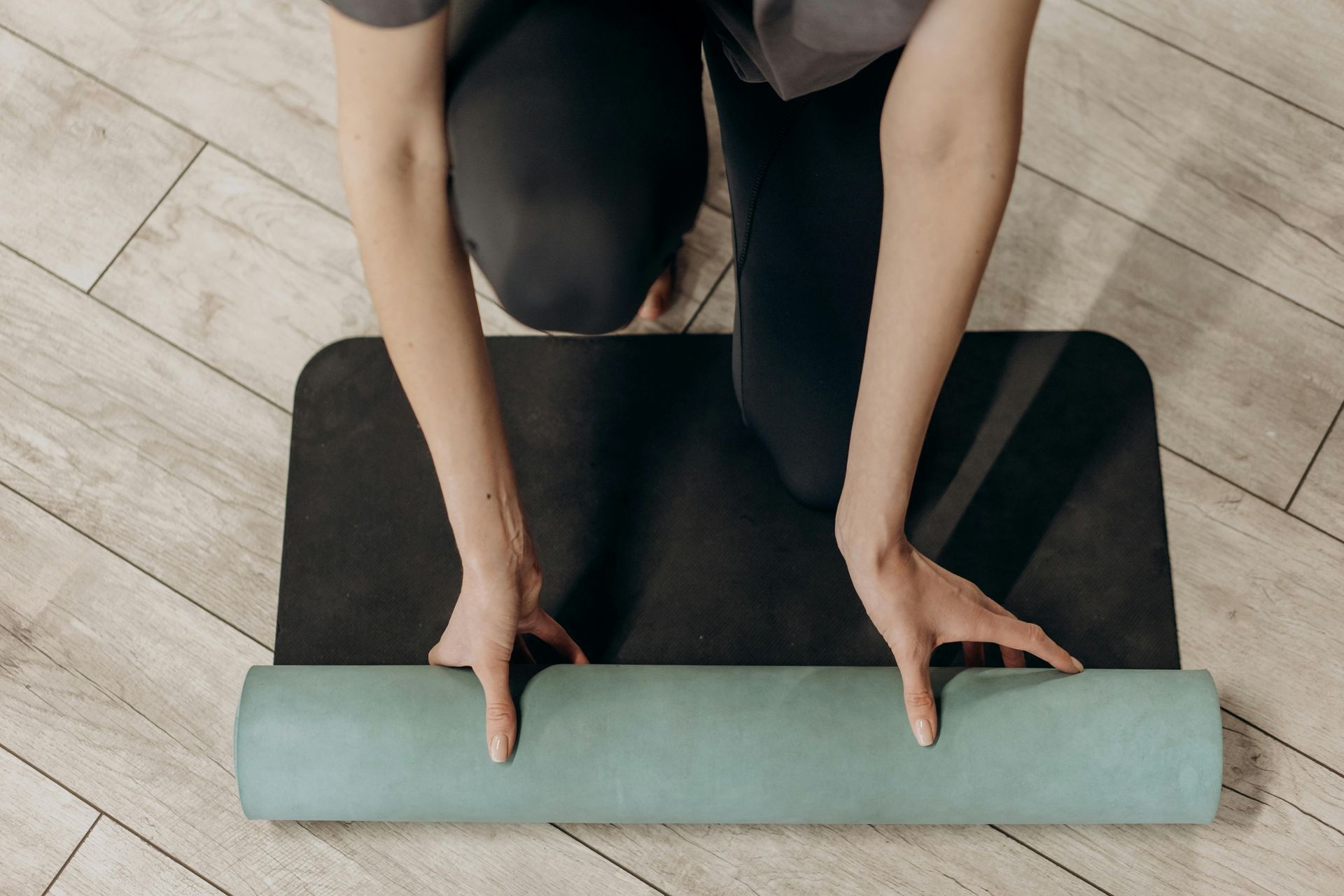 A person is kneeling down on a yoga mat.
