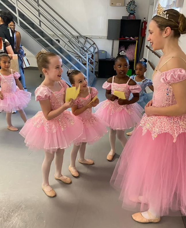 A group of young girls in pink tutus are standing next to each other in a room.
