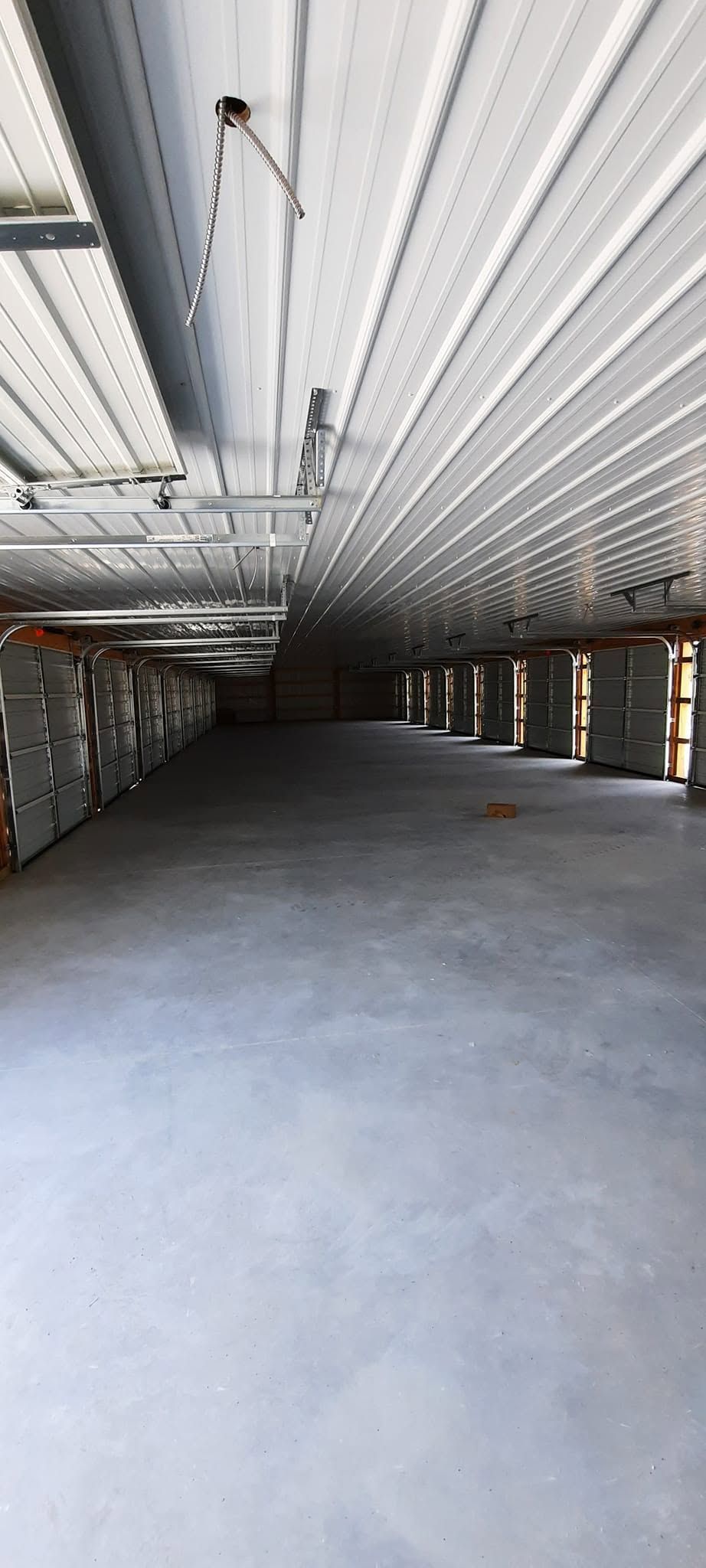 Empty industrial interior with exposed ceiling beams and a gray concrete floor