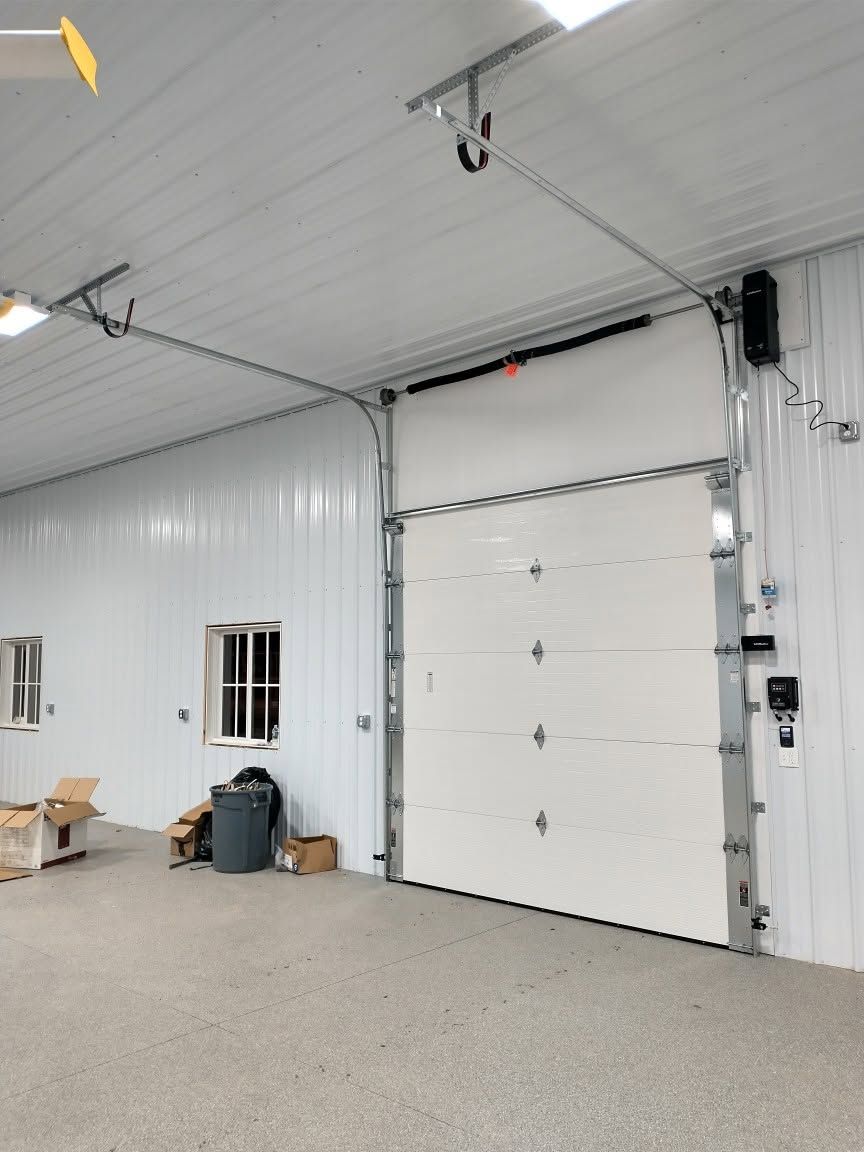 Interior of a clean workshop with white metal walls, large garage door, and concrete floor.
