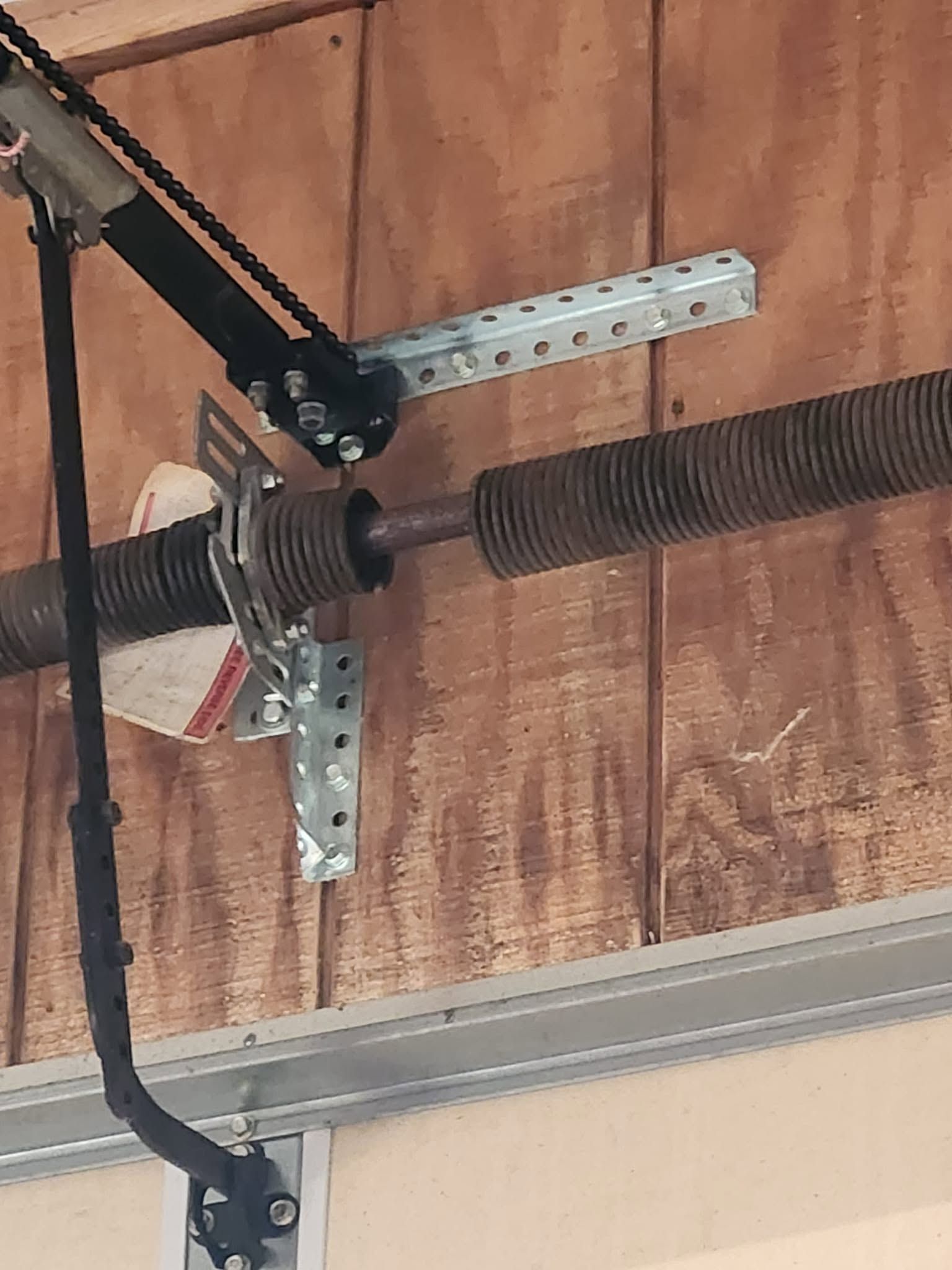 Garage door torsion spring and opener hardware mounted near the ceiling.