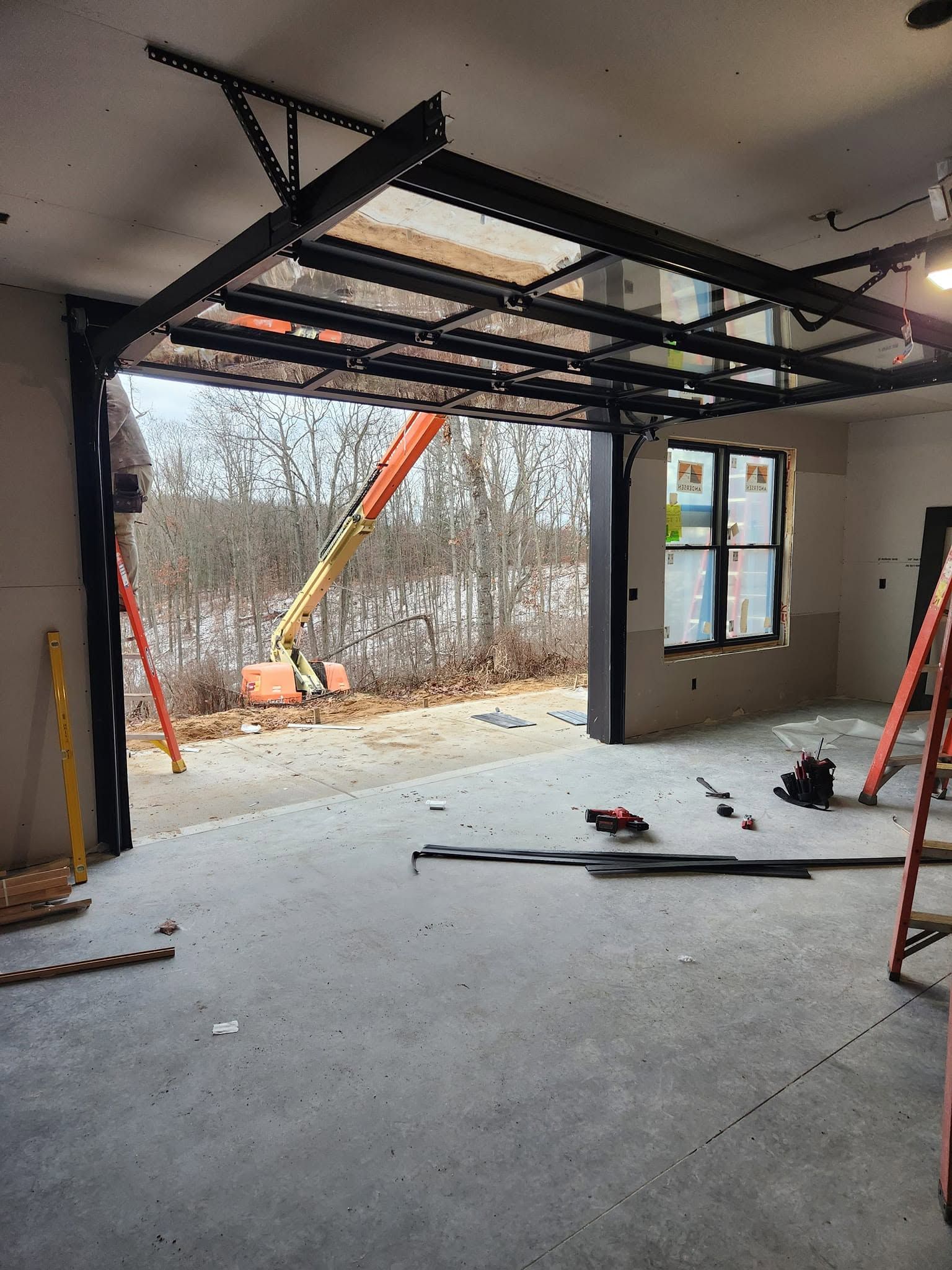 Renovated room with a large open wall, exposed framing, and construction equipment outside.