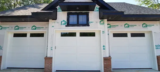 Three white garage doors with dark trim on a house exterior