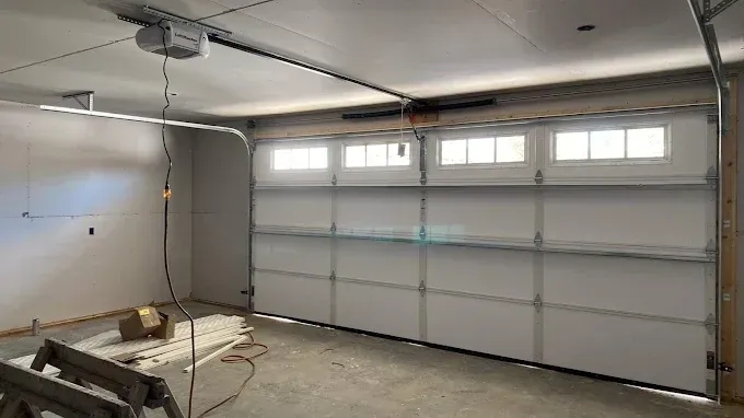 Empty garage interior with a closed white sectional door and a workbench on the left