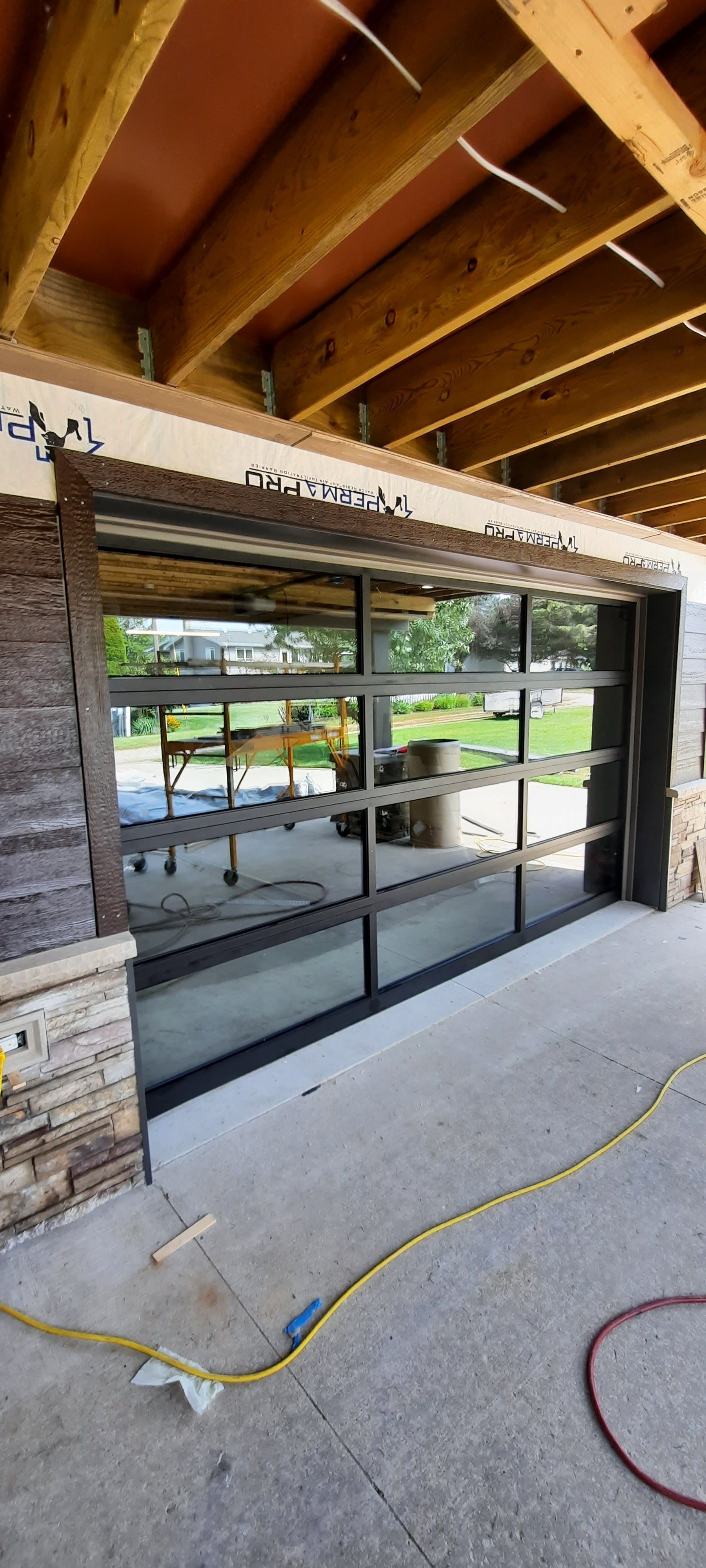 Partially constructed storefront with large sliding glass doors under exposed wooden beams