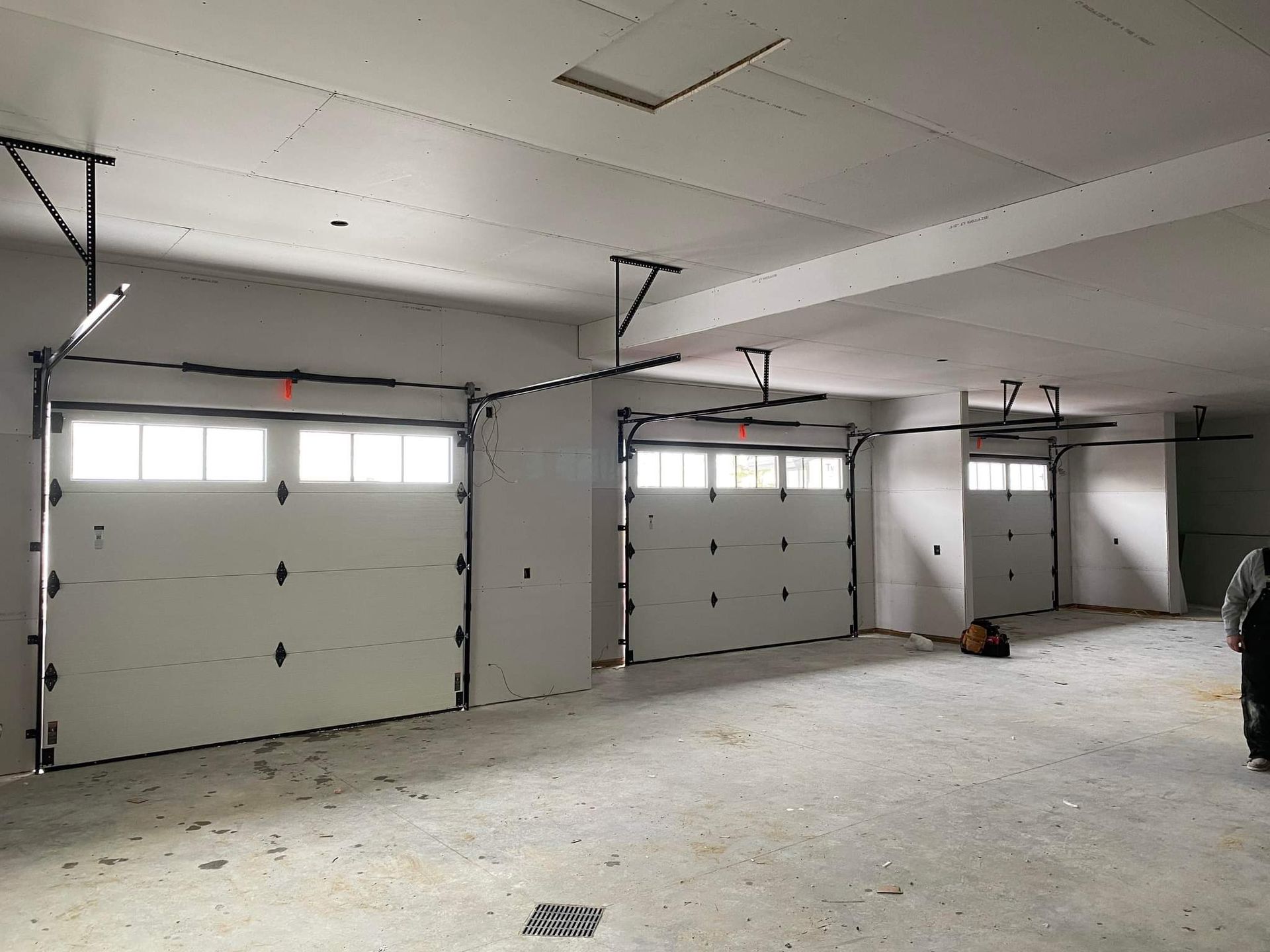 Empty garage interior with three white overhead doors and a concrete floor