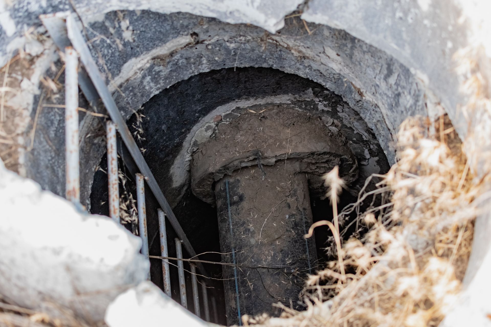 Exposed underground drainage structure with a pipe inside a concrete chamber during dry well repair 