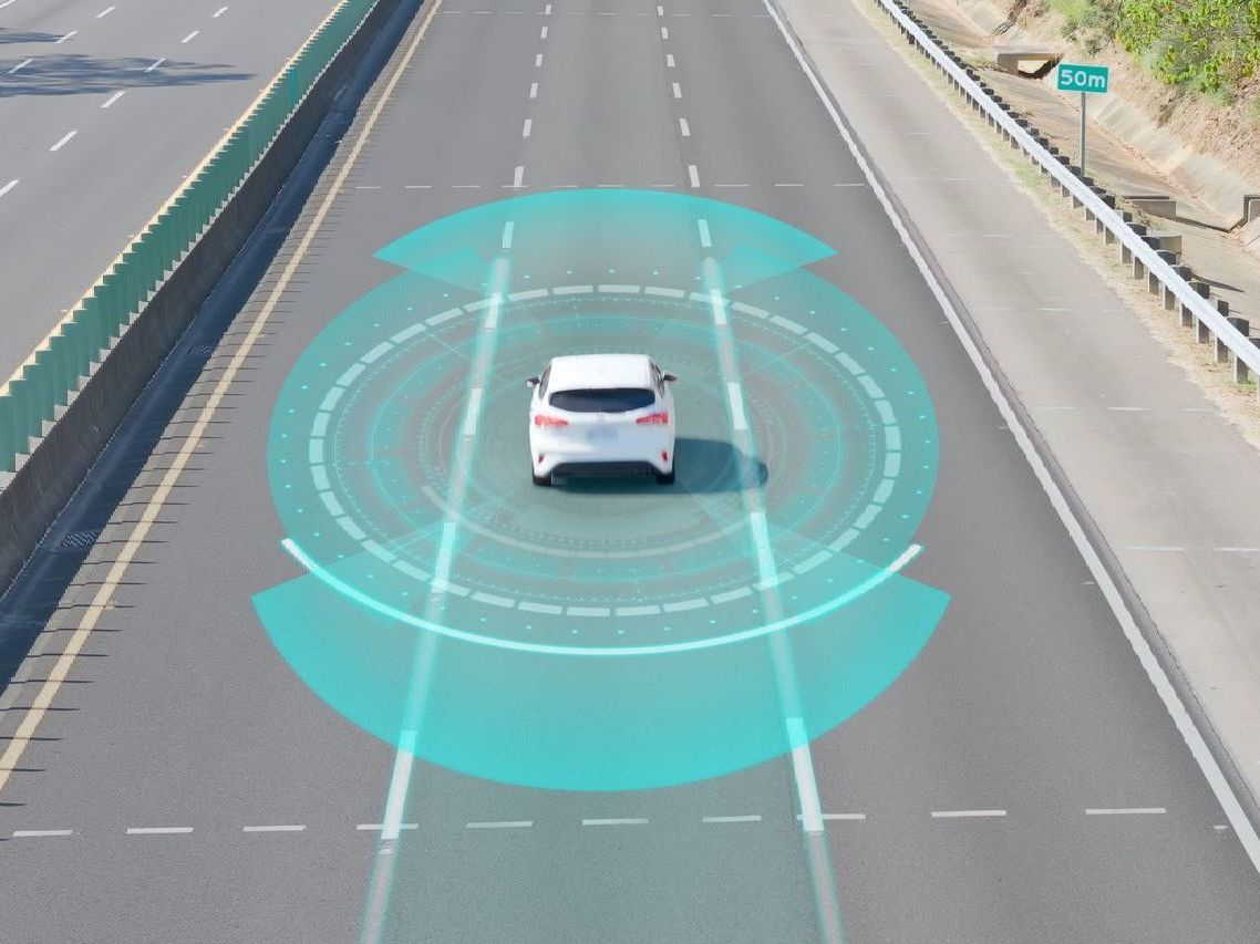 White car driving on a highway with blue lane-assist sensor graphics overlayed around it