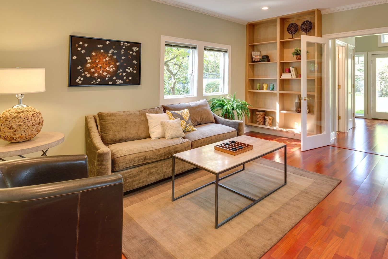 A living room with a couch , chairs , coffee table and shelves.