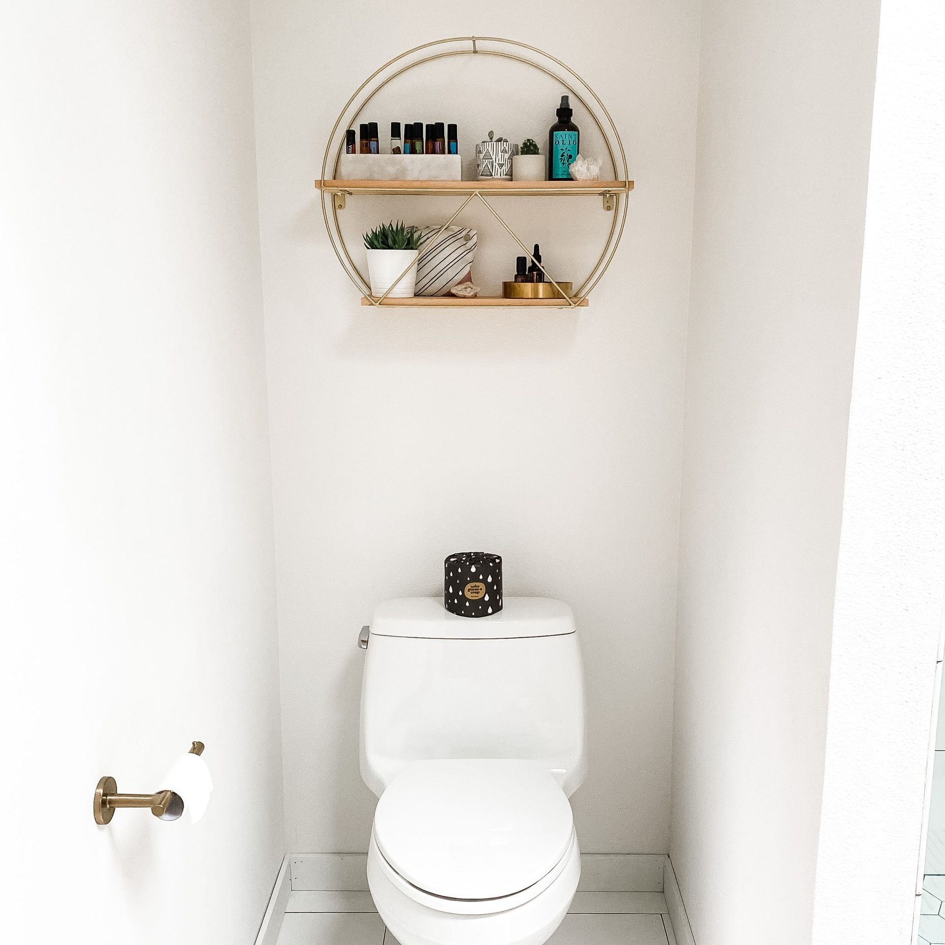 A toilet in a bathroom with a shelf above it