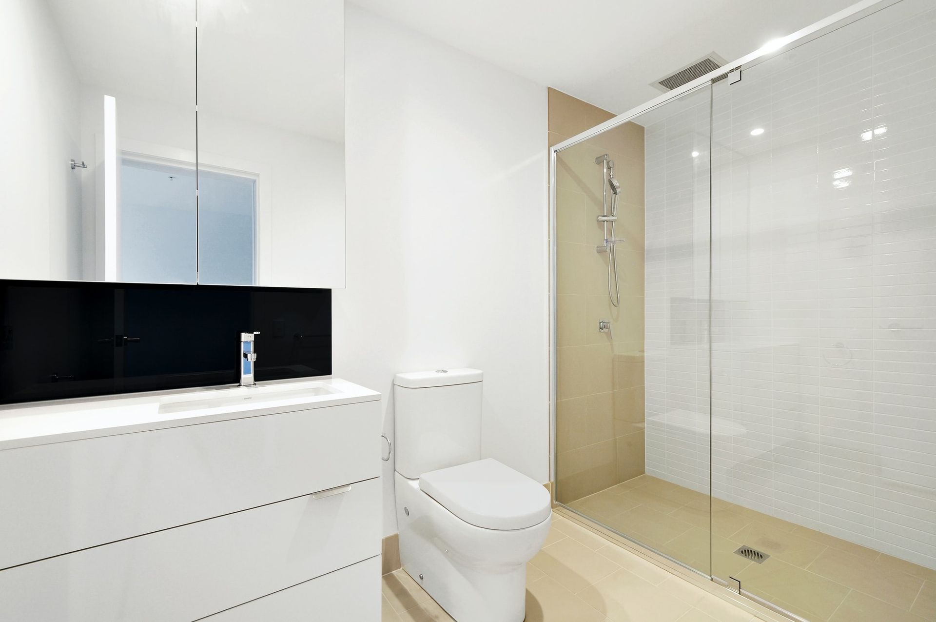 A bathroom with a toilet , sink and walk in shower.