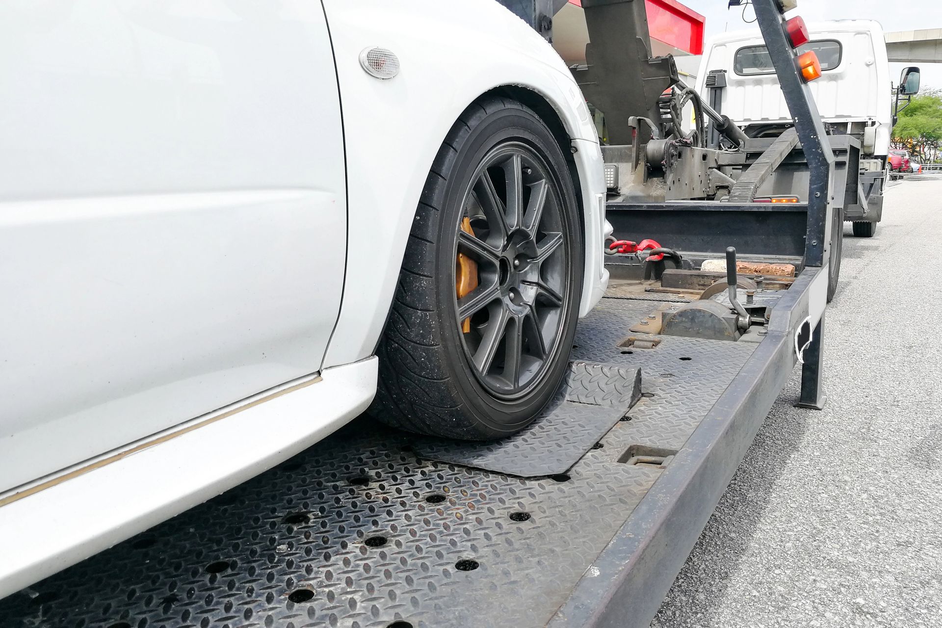 Auto sportiva bianca caricata sul pianale di un carro attrezzi a bordo strada.