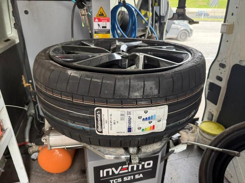 Pneumatici per auto impilati su una macchina equilibratrice all'interno di un'officina.