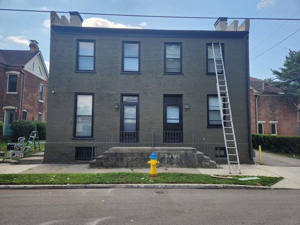 Brick duplex with a ladder leaning against the right side and a yellow fire hydrant on the sidewalk.