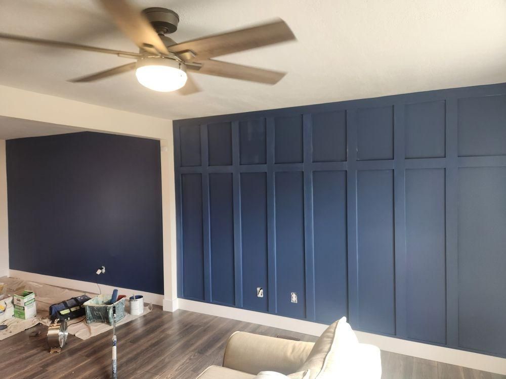 Blue paneled wall in a room with a ceiling fan and a table in the foreground