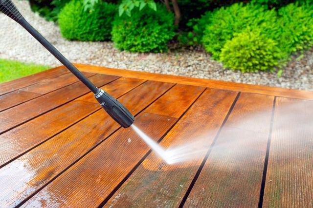 Pressure washing a wooden deck with water spray in an outdoor garden setting