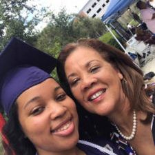 Graduate in purple cap smiling with woman at outdoor ceremony