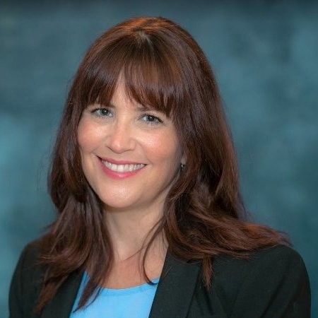 Smiling woman with brown hair against a blue studio backdrop