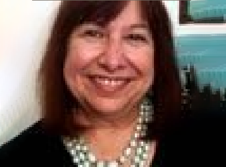 Smiling woman with dark hair wearing a pearl necklace against a light background
