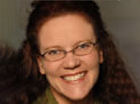 Smiling person with glasses and dark hair against a blurred background