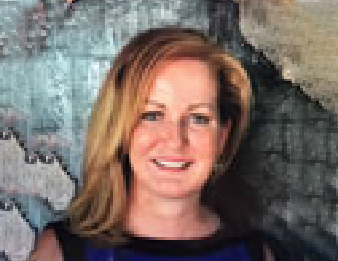 Smiling woman with blonde hair in a dark top against a textured gray-blue wall