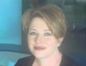 Smiling person with short light-brown hair against a blue and dark background