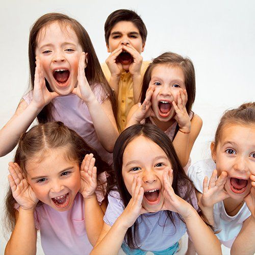 Six children grouped together, cupping their hands and shouting playfully toward the camera.