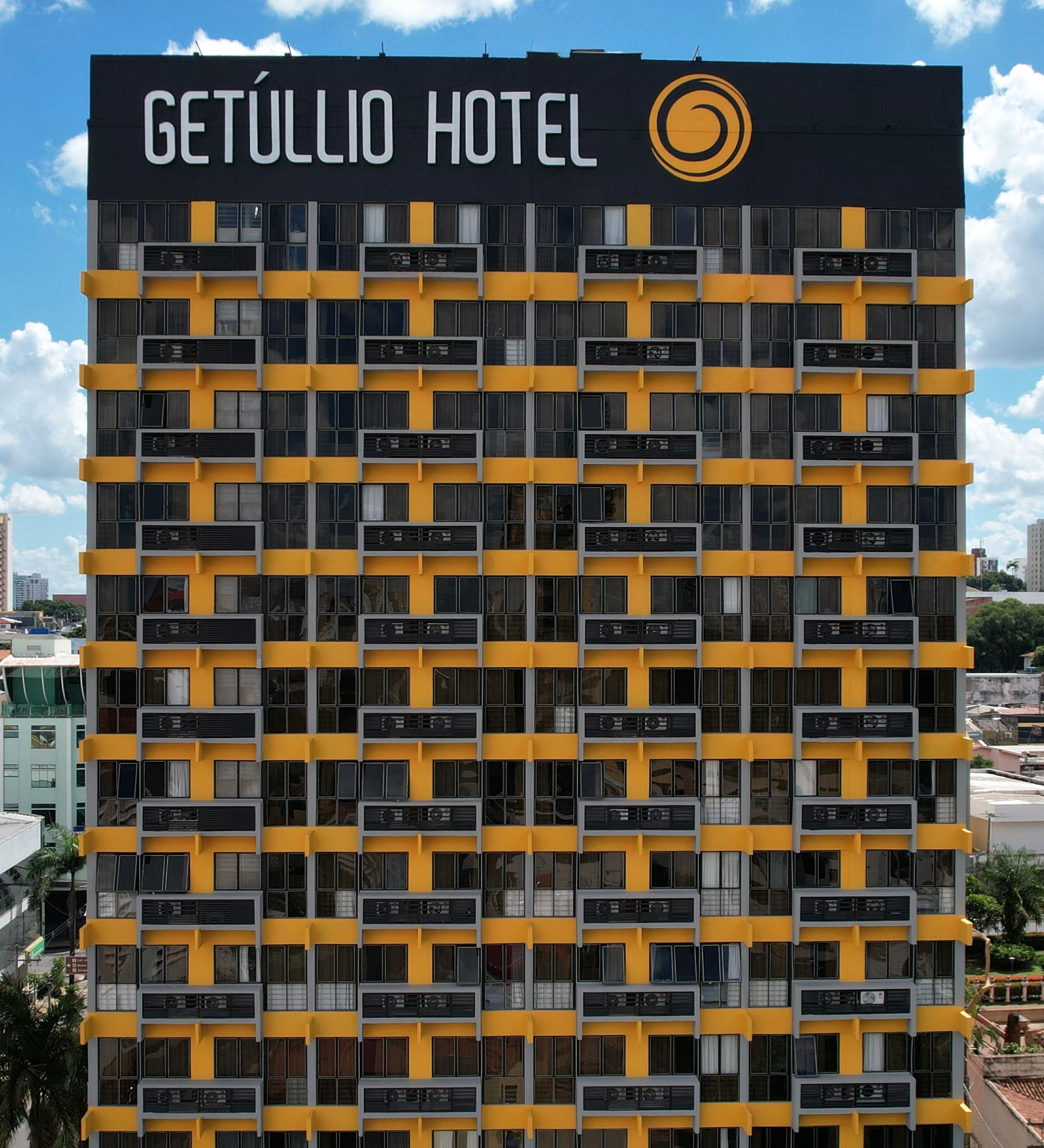 Fachada do edifício alto do Getúlio Hotel, com varandas pretas e laranjas e letreiro no terraço