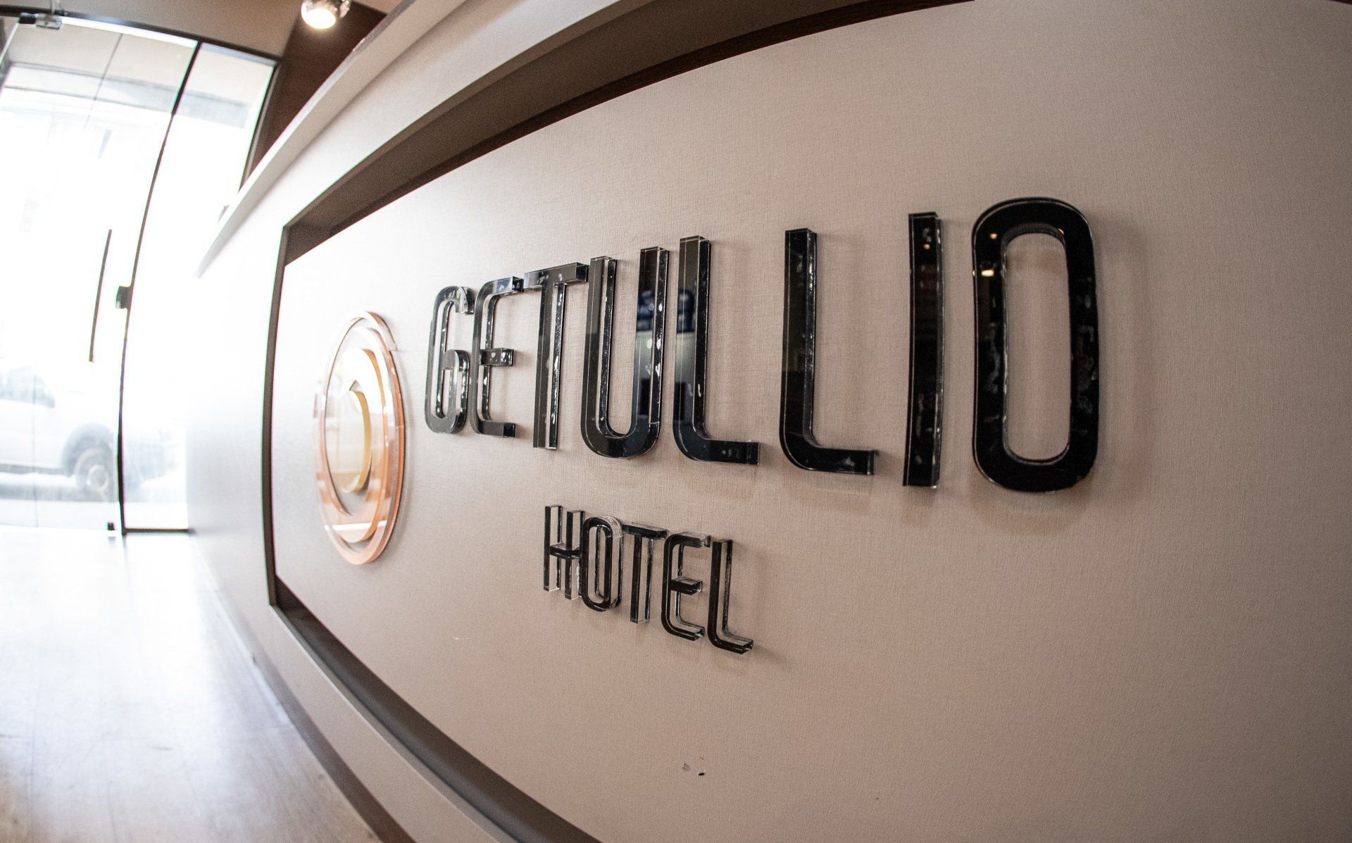 Placa do hotel com os dizeres “GETULLIO HOTEL” em uma parede de um corredor bem iluminado.