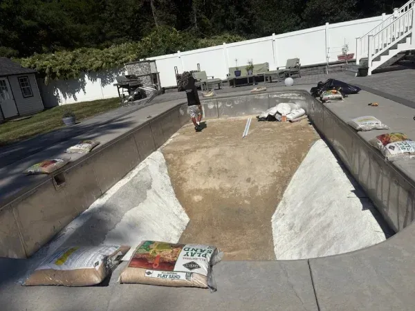 Concrete skate bowl with two people and scattered skateboards under a bright sky