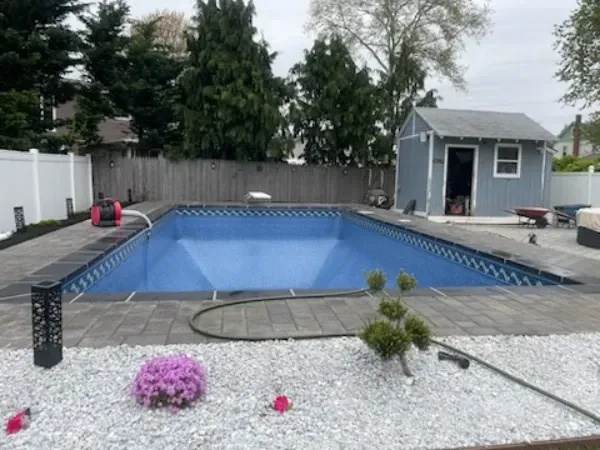 Backyard pool under construction with blue liner, wooden deck, and small shed nearby
