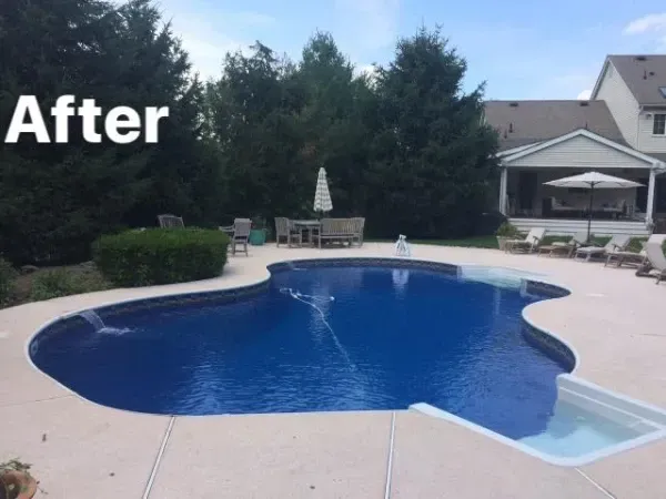 Backyard pool with blue water, pale deck, and patio furniture;