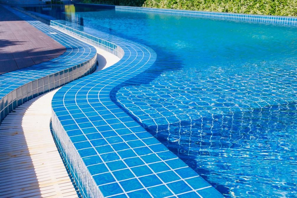 Curved blue-tiled swimming pool edge with clear water and a shallow ledge