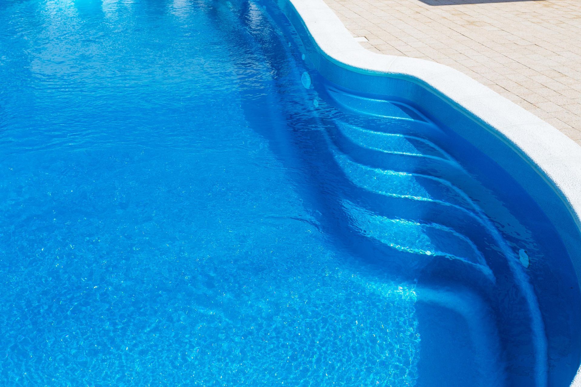 Blue swimming pool with curved steps and shimmering water