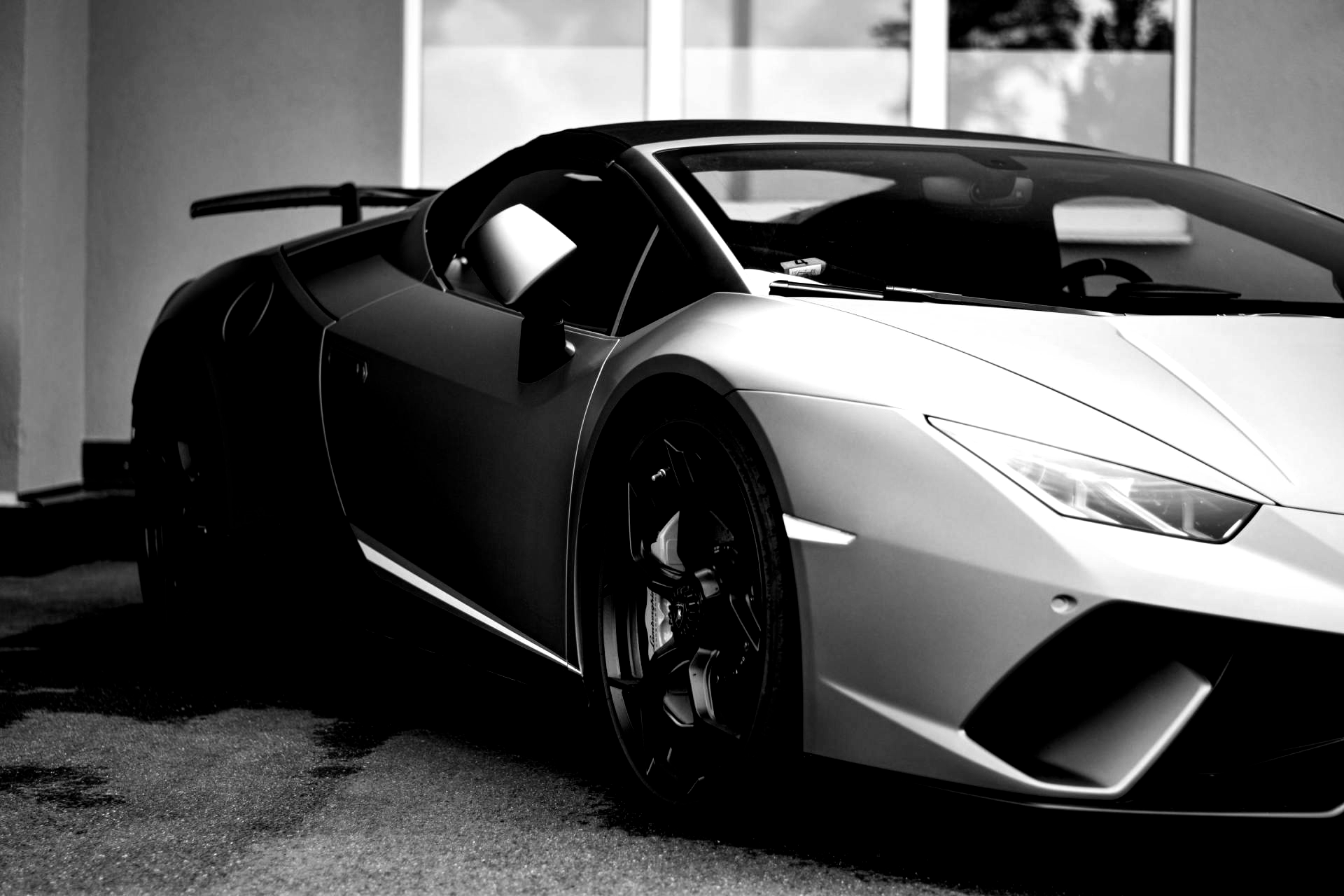 Black and white Lamborghini convertible parked in front of a building.