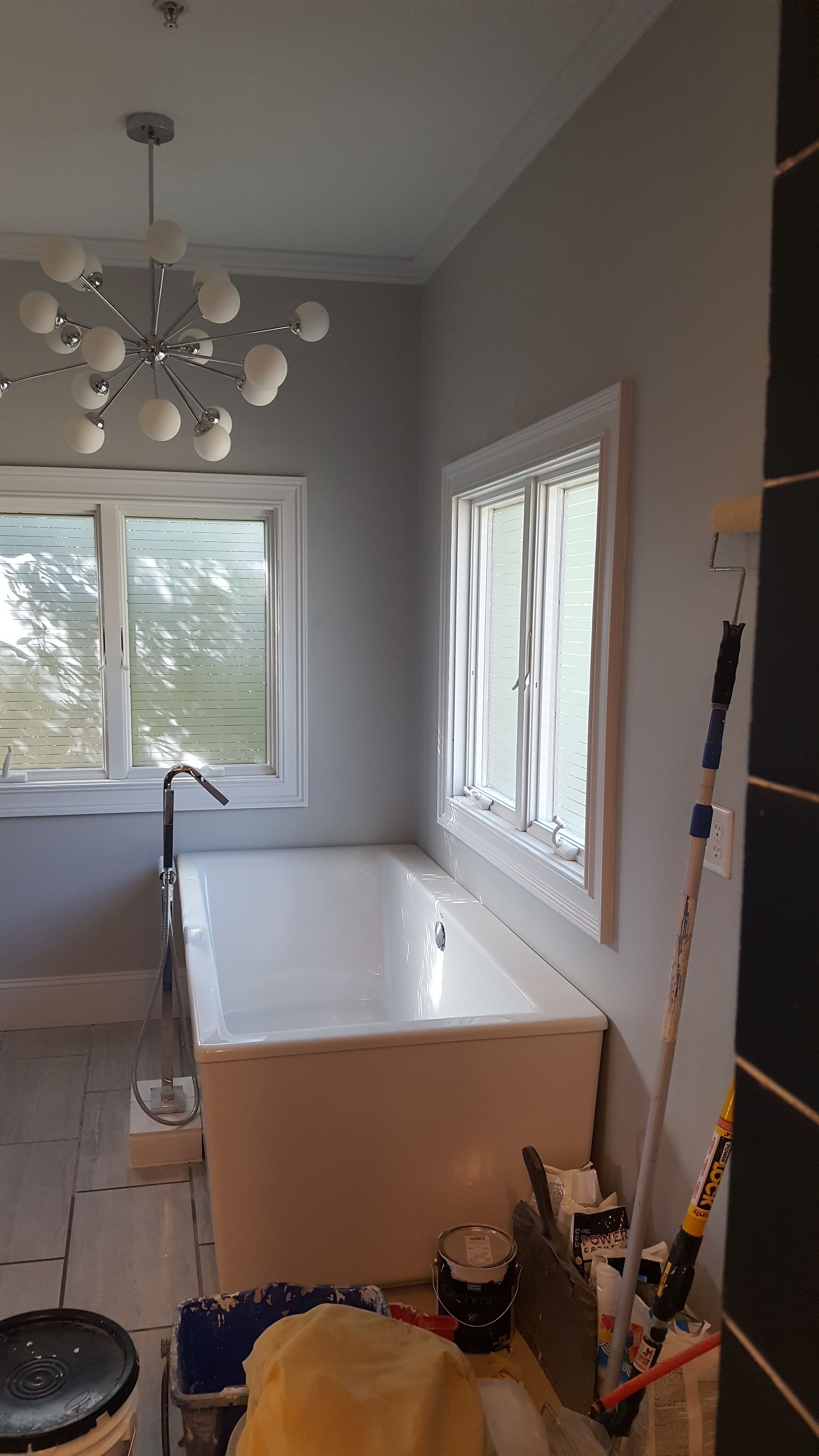 Kitchen under renovation with white cabinetry, tools, and a ladder by the window