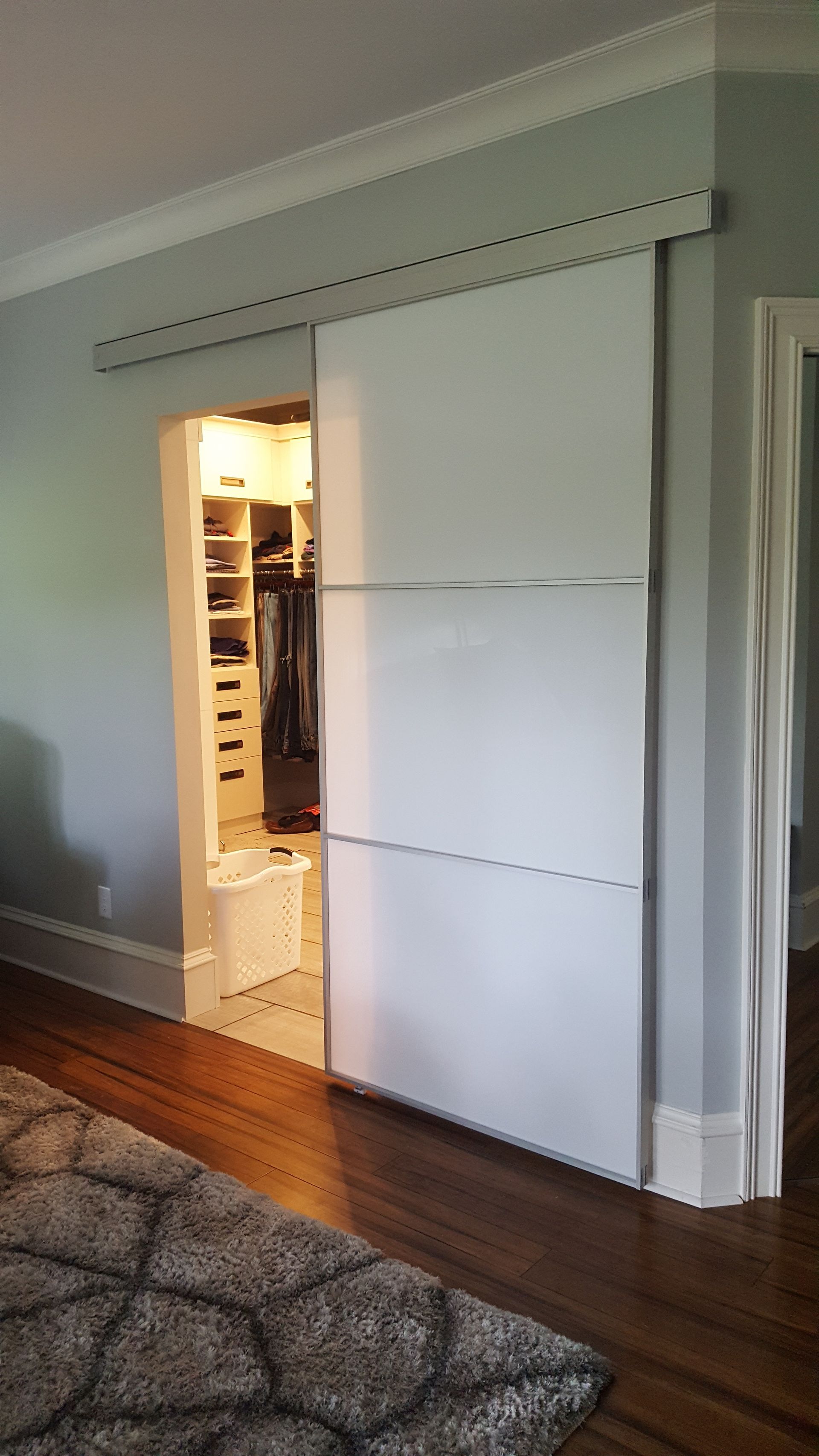 White sliding closet doors partially open in a room with hardwood floors and a patterned rug.