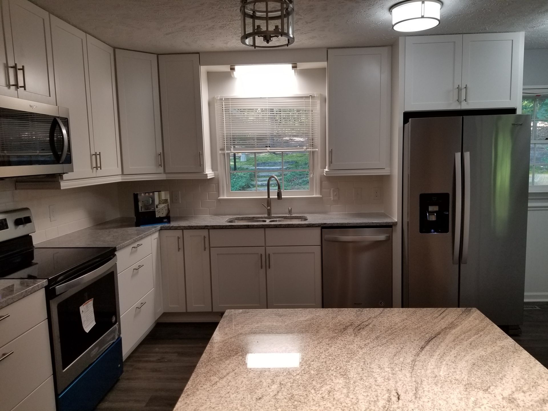 Bright modern kitchen with white cabinets, stainless appliances, and granite island countertop